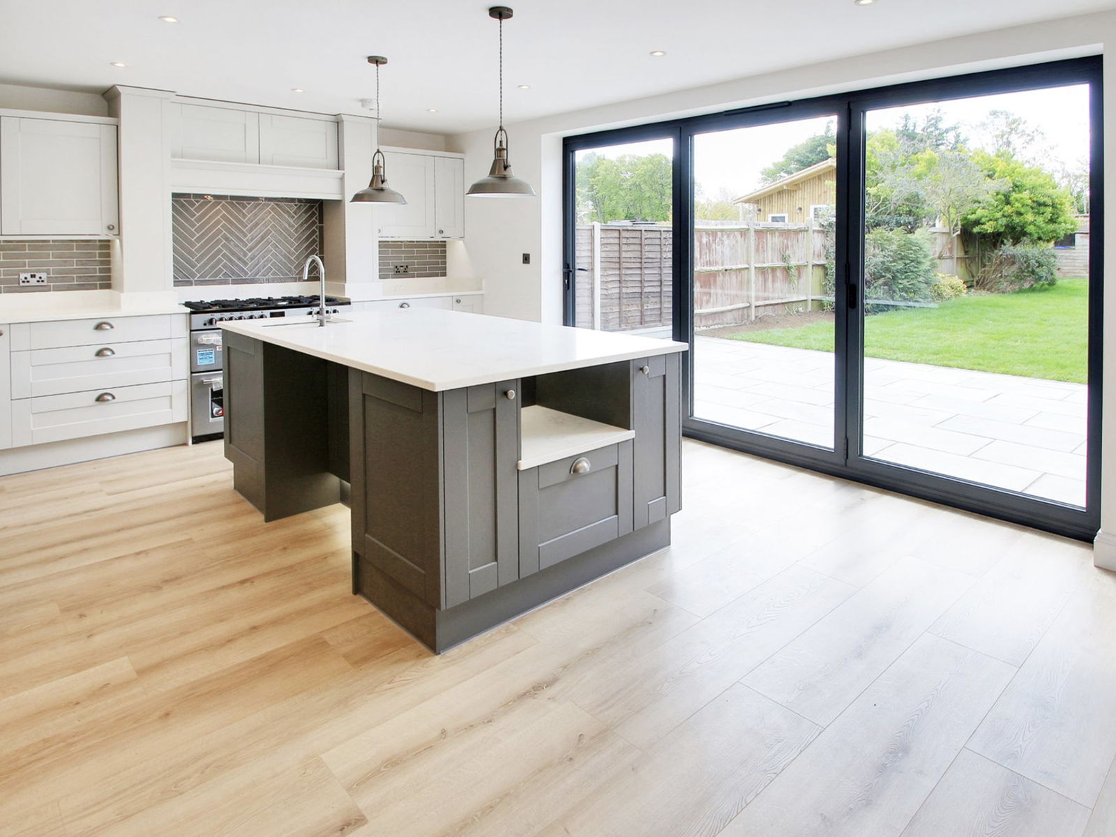An open plan kitchen inside a completed chalet conversion, with an island and sliding doors to the garden