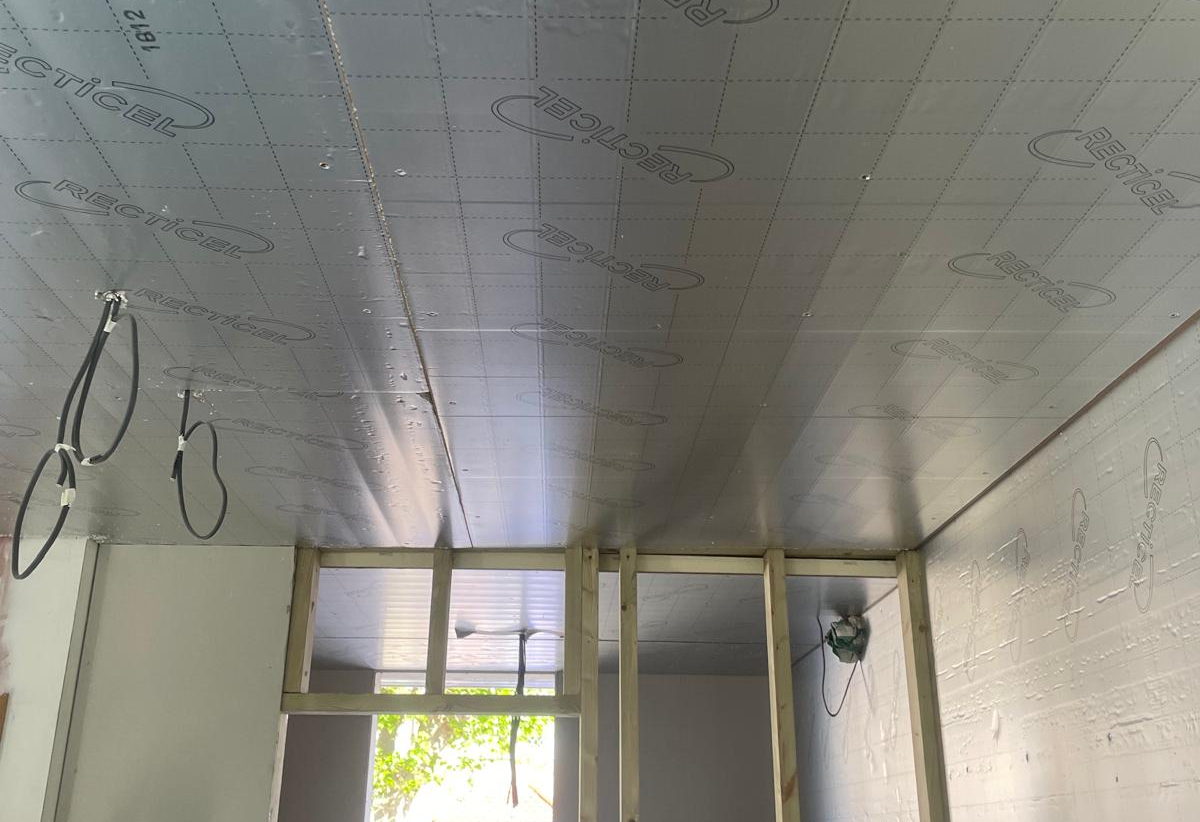A garage conversion during the build, with insulation boards fixed to the ceiling and walls and the new front wall studded out