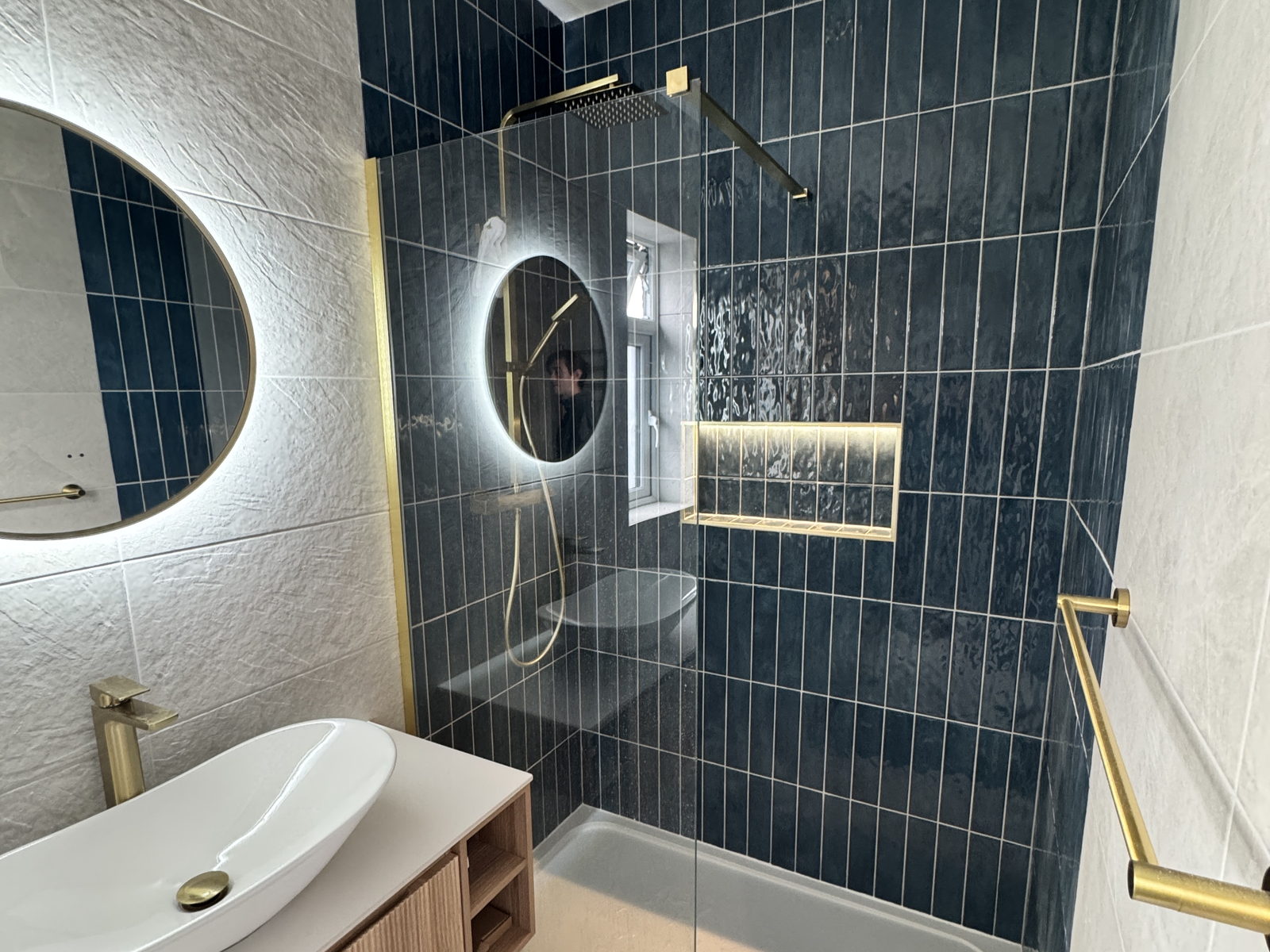A shower room built into a garage conversion, with deep blue vertical tiling, brushed brass fittings and a walk in shower, built by LD&C Homes