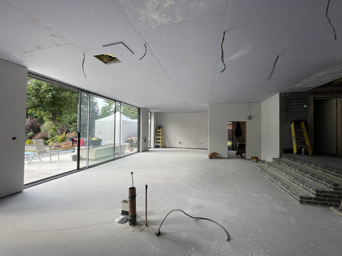 The ground floor plastered out with the sliding glazing installed, underfloor heating laid and the floor screed down, by LD&C Homes